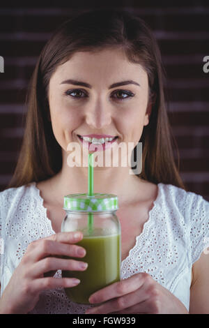 Hübsche Frau, nippen an grüner Saft Stockfoto