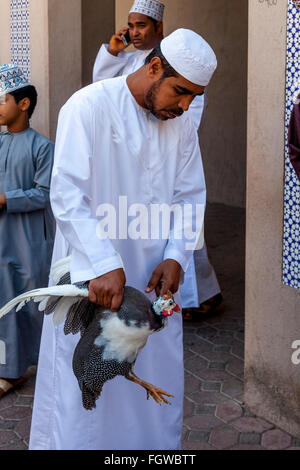 Ein omanischer Mann kauft einen Vogel am Freitag Vogel Markt, Nizwa, Ad Dakhiliyah Region, Oman Stockfoto