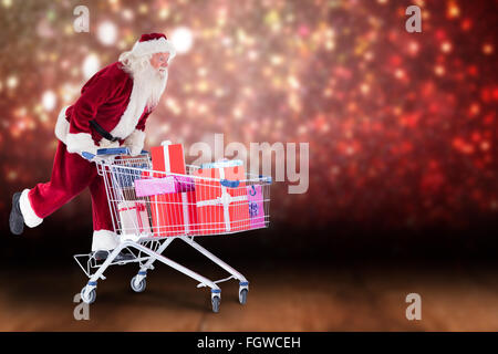 Zusammengesetztes Bild von Santa schiebt einen Einkaufswagen Stockfoto