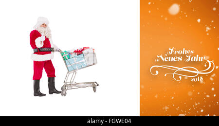 Zusammengesetztes Bild des positiven Santa, die Geschenke mit einem Trolley zu liefern Stockfoto