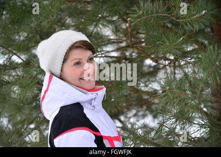 Frau im Sportjacke und Hut im Winter Kiefernwald Stockfoto