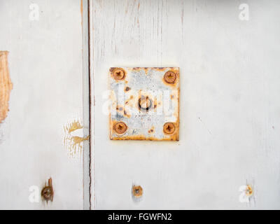 alten Metallplatte befestigt mit Schrauben auf weißem Holz Tisch Stockfoto