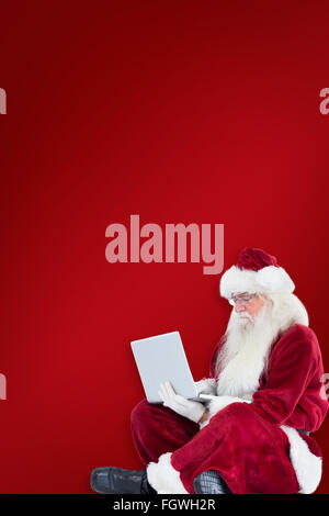 Zusammengesetztes Bild von Santa sitzt und einen laptop Stockfoto