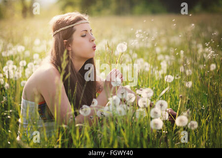 Wunderschöne Hippie-Frau bläst Löwenzahn Blumen. Natur-Harmonie Stockfoto