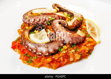 Oktopus gekocht auf dem Grill, vorher mariniert in Olivenöl, Oregano, Salz und Pfeffer. Auf einem Bett aus Tomaten, Karotten und Lauch Stockfoto