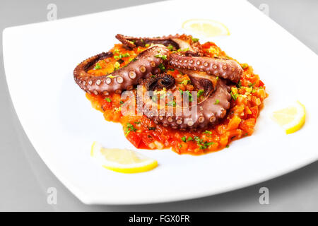 Oktopus gekocht auf dem Grill, vorher mariniert in Olivenöl, Oregano, Salz und Pfeffer. Auf einem Bett aus Tomaten, Karotten und Lauch Stockfoto