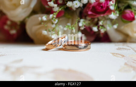 Hochzeit goldene Ringe auf einem Hintergrund von roten Rosen Stockfoto