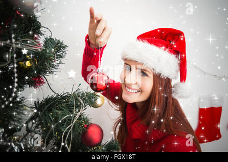 Zusammengesetztes Bild von festlichen Redhead Christbaumkugel am Baum hängen Stockfoto