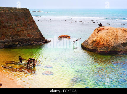Jungen schwimmen und springen in den Ozean aus dem Felsen. Sri Lanka Stockfoto