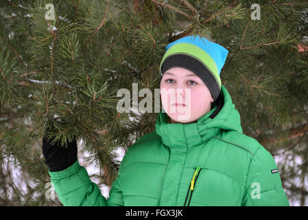 Junge Teenager in grüner Jacke im Winter Kiefernwald Stockfoto