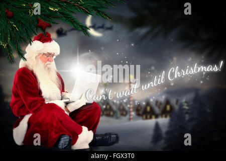 Zusammengesetztes Bild von Santa sitzt und einen laptop Stockfoto