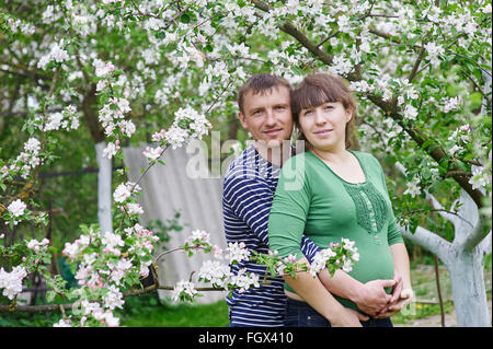 Mann und seine schwangere Frau im Frühjahr blühenden Garten Stockfoto