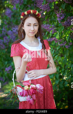 Junge Frau mit Kranz und mit lila Blüten im Frühling Stockfoto