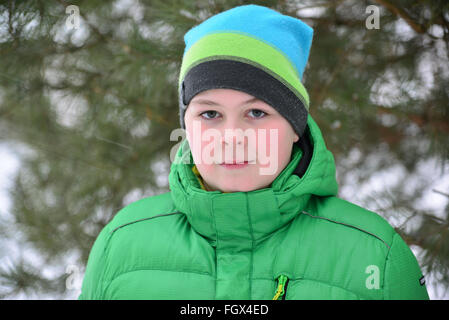 Junge Teenager in grüner Jacke im Winter Kiefernwald Stockfoto