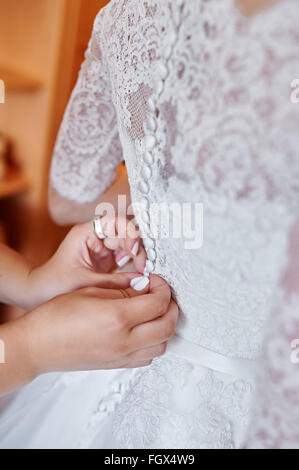 Brautjungfern helfen die Braut eine Hochzeitskleid tragen Stockfoto