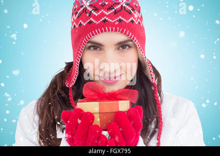 Zusammengesetztes Bild der lächelnde Brünette im Winterkleidung mit Geschenk Stockfoto