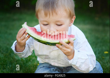 kleiner Junge Essen Wassermelone im Sommergarten Stockfoto