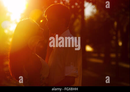 Junges Paar Silhouette umarmt und sahen einander im Freien auf den Sonnenuntergang Stockfoto