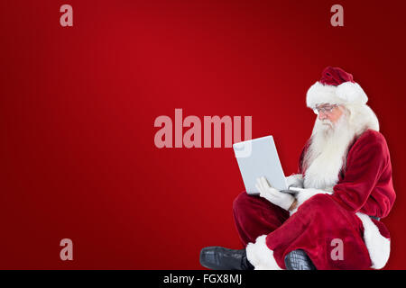 Zusammengesetztes Bild von Santa sitzt und einen laptop Stockfoto