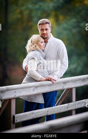 Junge, blonde Frau mit ihrem Ehemann im Park auf der Brücke Stockfoto