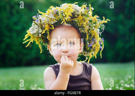 Schöne glückliches kleines Mädchen in einem Kranz auf einer Wiese auf die Natur Stockfoto