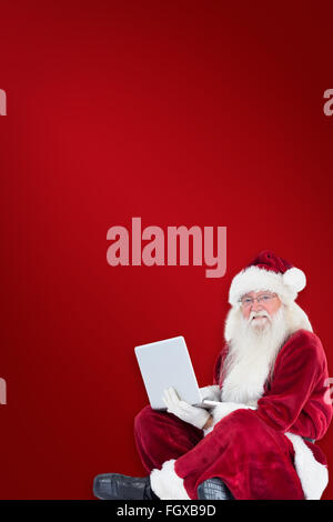 Zusammengesetztes Bild von Santa sitzt und einen laptop Stockfoto