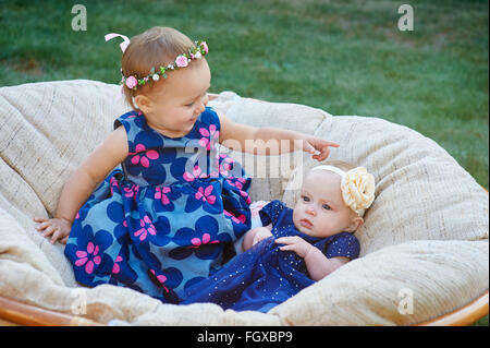 Zwei lustige Kinder sitzen auf dem weichen Licht Stuhl zusammen im Frühlingspark Stockfoto