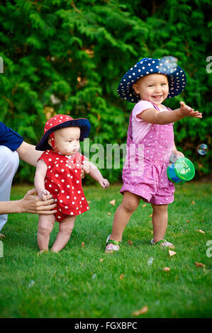 Zwei Mädchen spielen auf dem grünen Rasen im Frühlingsgarten Stockfoto