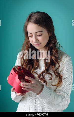 schöne Frau, wenn man bedenkt ein Geschenk in Form von Herzen zum Valentinstag Stockfoto