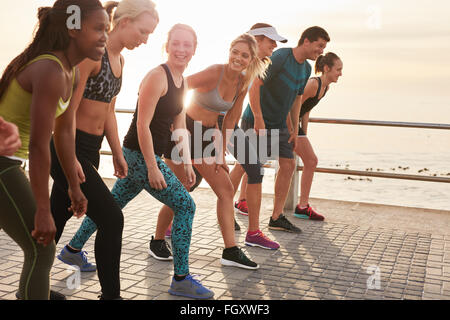 Gruppe junger Sportler in Startposition. Passen Sie Jugendlichen Vorbereitung für Rennen entlang Meer. Stockfoto