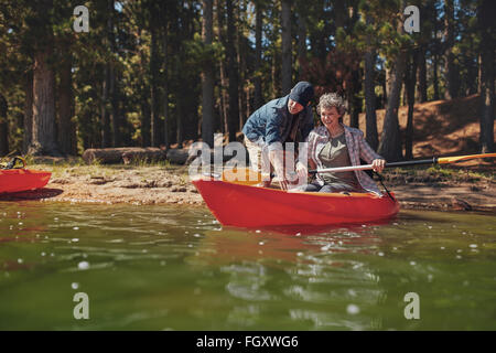 Porträt von Reife Frau lernen, im Kajak zu rudern. Man lehrt Frau am See Kajak. Stockfoto