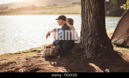 Porträt des mittleren gealterten paar sitzt unter einem Baum in der Nähe des Sees. Älteres paar entspannende auf ihrem Campingplatz. Stockfoto