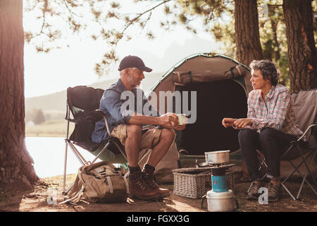 Porträt der glückliche ältere Camper Kaffeegenuss am See. Älteres paar entspannende auf ihrem Campingplatz. Stockfoto