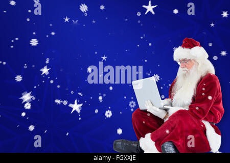 Zusammengesetztes Bild von Santa sitzt und einen laptop Stockfoto