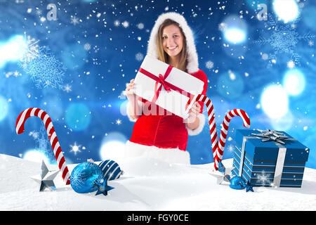 Zusammengesetztes Bild von hübschen Santa Mädchen stehend mit Geschenk Stockfoto