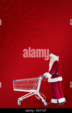 Zusammengesetztes Bild von Santa schiebt einen Einkaufswagen Stockfoto