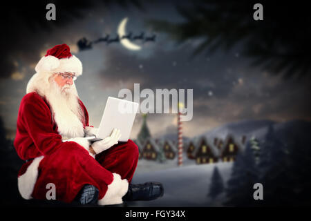 Zusammengesetztes Bild von Santa sitzt und einen laptop Stockfoto