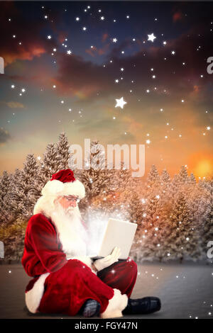 Zusammengesetztes Bild von Santa sitzt und einen laptop Stockfoto