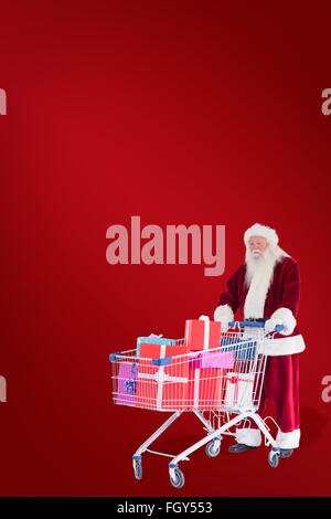 Zusammengesetztes Bild von Santa schiebt einen Einkaufswagen mit Geschenken Stockfoto