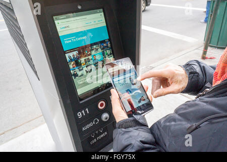 Eine Frau benutzt einen LinkNYC Kiosk Zugriff auf das Internet über ihr Smartphone in New York auf Samstag, 20. Februar 2016. Mehr als 7500 Kioske sind zu installierten ersetzen Stand allein Münztelefon Kioske bieten kostenfreies WLAN, Internet-Zugang über einen Touch-Screen, Telefon geladen und kostenlos telefonieren. Das System soll durch Werbung auf den Seiten der Kioske unterstützt werden. (© Richard B. Levine) Stockfoto