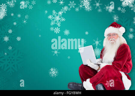 Zusammengesetztes Bild von Santa sitzt und einen laptop Stockfoto