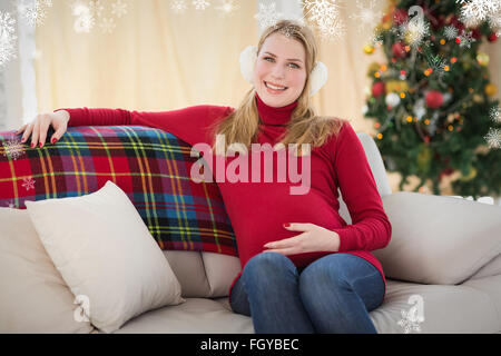 Zusammengesetztes Bild schöne schwangere Frau sitzen auf einer couch Stockfoto