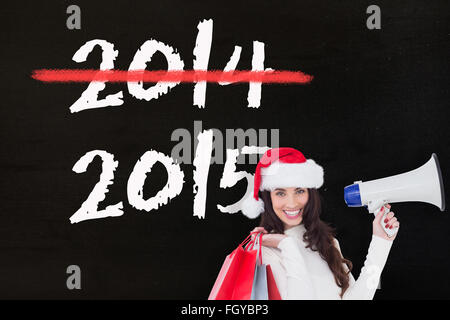 Zusammengesetztes Bild des lächelnden Brünette holding Geschenktüten und Megaphon Stockfoto