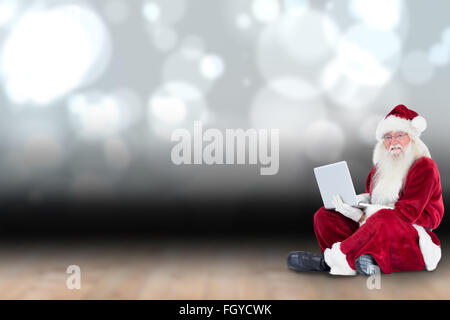 Zusammengesetztes Bild von Santa sitzt und einen laptop Stockfoto