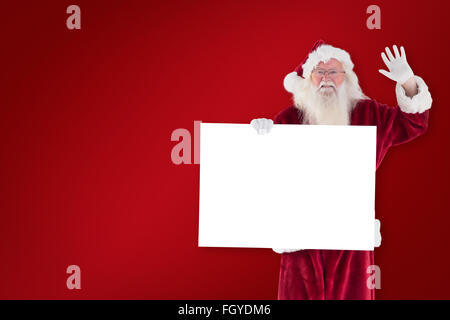 Zusammengesetztes Bild von Santa hält ein Schild und winkt Stockfoto