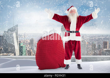 Zusammengesetztes Bild von Santa auf verschneiten Felsvorsprung stehend Stockfoto