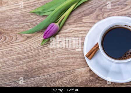 Tasse Kaffee und Violet Tulip auf einem hölzernen Hintergrund Stockfoto