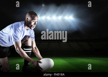 Zusammengesetztes Bild der Rugbyspieler wegsehen und Ball am Abschlag treten dabei Stockfoto