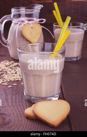 Bananen-Smoothie mit herzförmigen Keksen auf hölzernen Hintergrund Stockfoto
