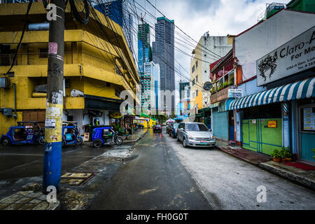 Eine schmale Straße und entfernten Wolkenkratzer in Poblacion, Makati, Metro Manila, Philippinen. Stockfoto